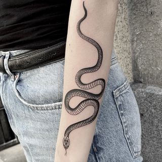 Blackwork tattoo of a snake on a forearm.