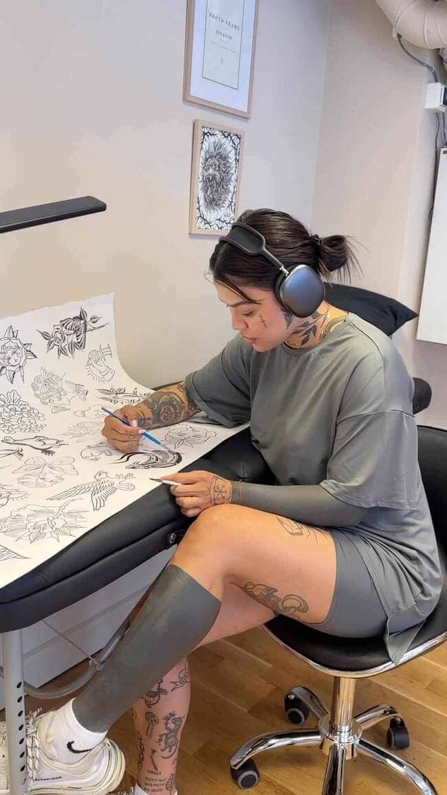 Tattoo artist drawing tattoo designs on paper.