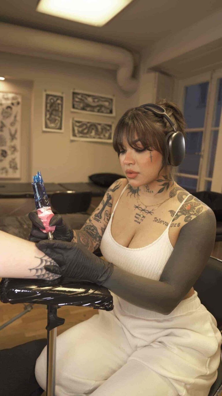 A tattoo artist doing a tattoo a on someones arm.