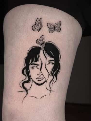 Blackwork tattoo of a female face splitted in two pieces with 3 butterflies flying over it.