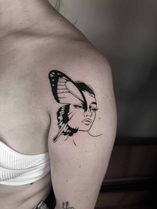 Blackwork tattoo on a womans shoulder, of a womans face combained with a butterfly wing.