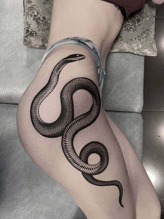 Blackwork tattoo of a snake on a leg.