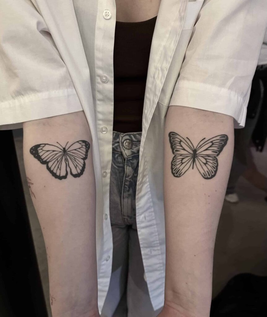 Two healed tattoos on each of a persons arms of two butterflies.