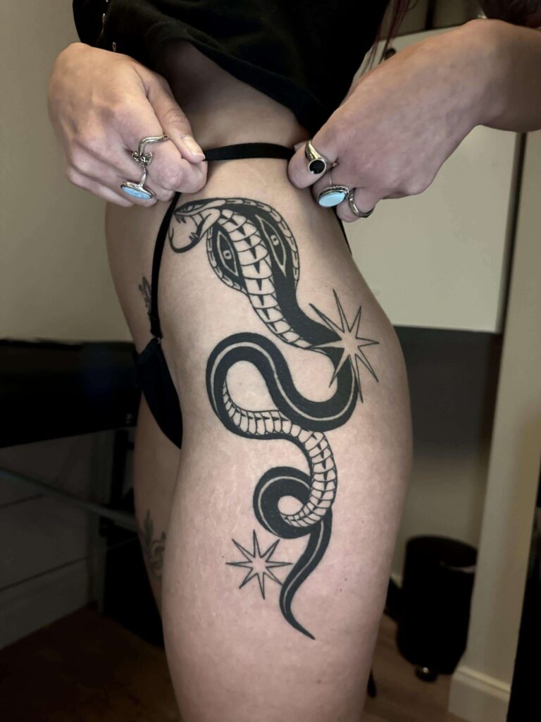 Healed tattoo on a leg with a black snake.