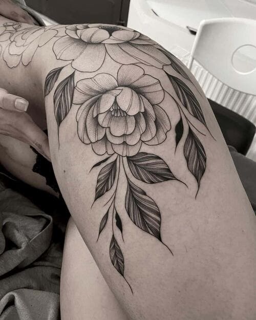 Fine line tattoo on a leg of flowers and leaves.