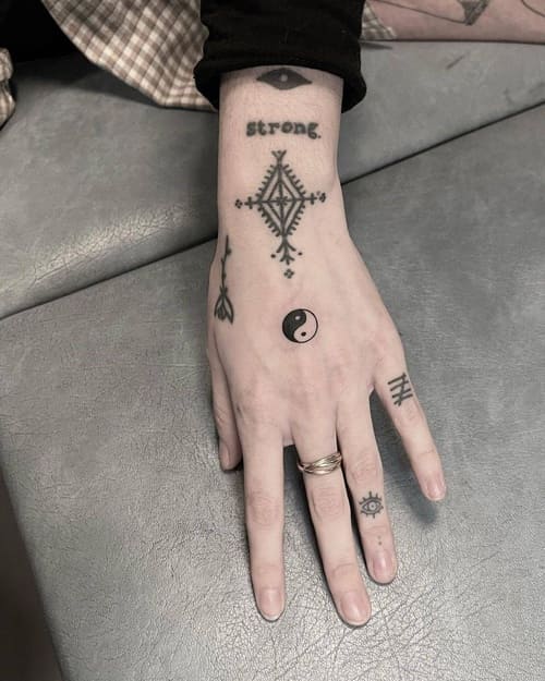 minimalist tattoos of symbols on a hand and fingers.