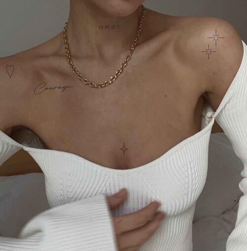 Minimalist tattoos of text and symbols on a womans upper body.