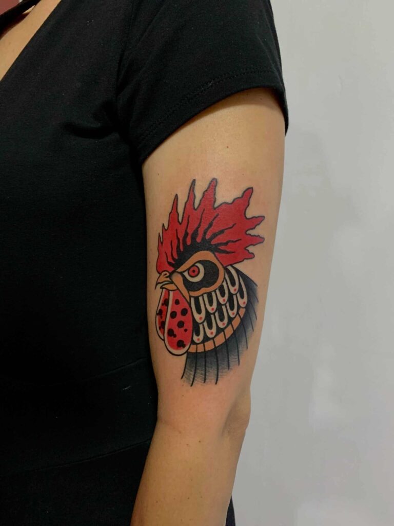 Traditional tattoo on a arm with a red rooster that is angry.